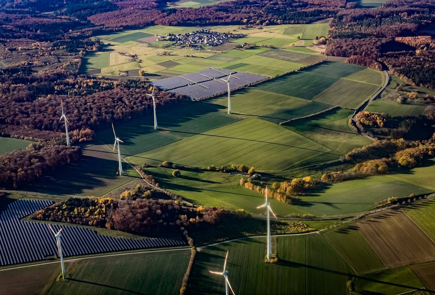 Solcellepark og vindturbiner i jordbrukslandskap sett ovenfra